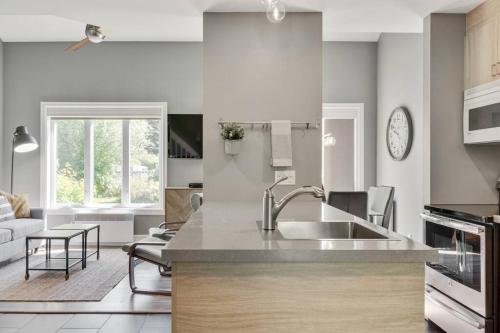a kitchen with a sink and a living room at INITIAL - ZÉPHYR - Mont-Sainte-Anne in Beaupré