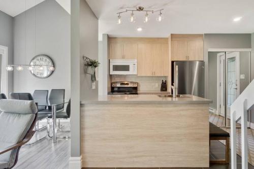 a kitchen with a counter top and a dining room at INITIAL - ZÉPHYR - Mont-Sainte-Anne in Beaupré