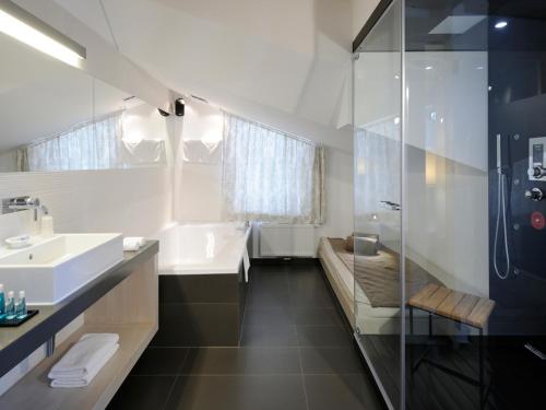 y baño con bañera, lavamanos y ducha. en Cresta.Alpin.Sport.Hotel, en Lech am Arlberg