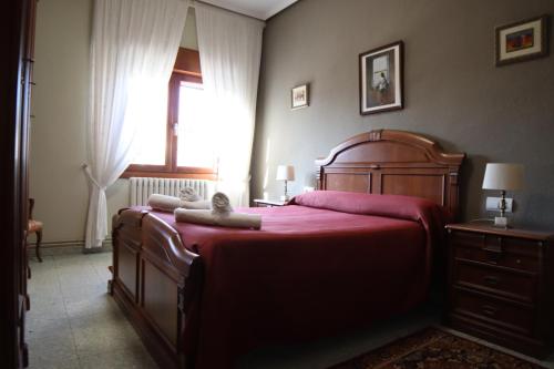 a bedroom with a large wooden bed with red sheets at Alojamiento Rural Ribaforada in Ribaforada