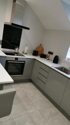 a white kitchen with a stove and a sink at Modern 3-Bed Apartment in Magherafelt Sleeps 8 in Magherafelt