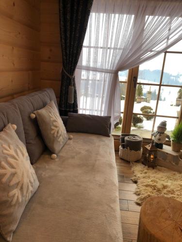 a living room with a couch and a large window at Domek Tatrzańska Zyngierka z Jacuzzi in Ząb