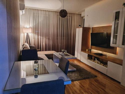 ein Wohnzimmer mit einem Sofa, einem Tisch und einem TV in der Unterkunft Zara Apartman in Bijeljina