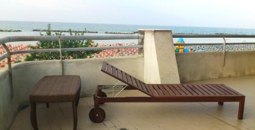 a bench and a chair on a balcony with the beach at Residence Le Terrazze Sul Mare in San Mauro a Mare