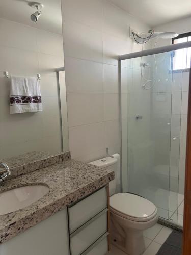 a bathroom with a toilet and a sink and a shower at Apto novo Imperia Lounge pé-na-areia Itacimirim in Itacimirim