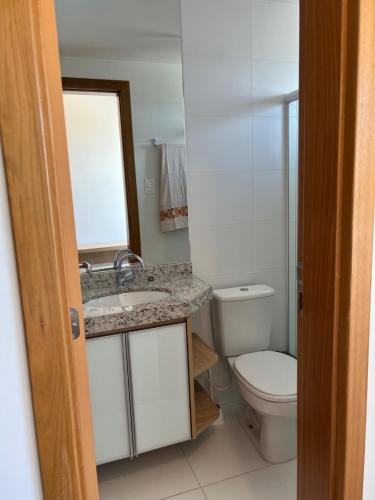 a bathroom with a sink and a toilet and a mirror at Apto novo Imperia Lounge pé-na-areia Itacimirim in Itacimirim