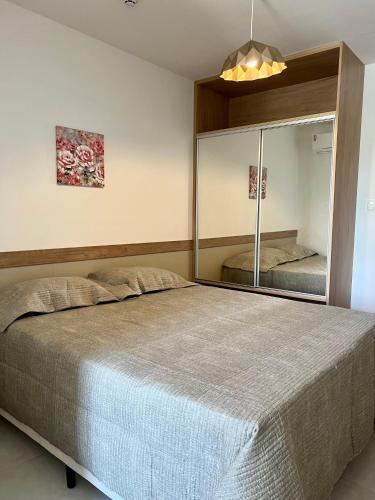 a bedroom with a large bed and a mirror at Apto novo Imperia Lounge pé-na-areia Itacimirim in Itacimirim