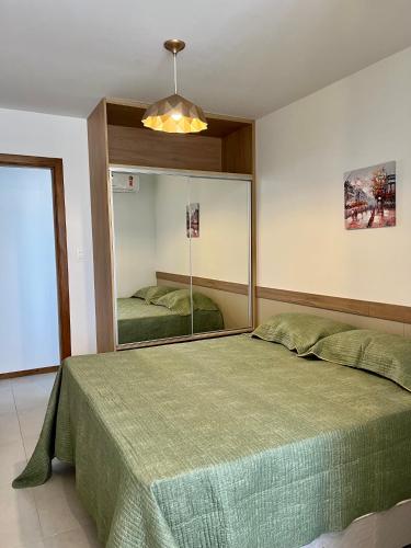 a bedroom with a large green bed and a mirror at Apto novo Imperia Lounge pé-na-areia Itacimirim in Itacimirim