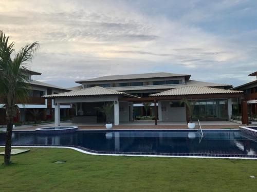 a house with a swimming pool in front of a house at Apto novo Imperia Lounge pé-na-areia Itacimirim in Itacimirim