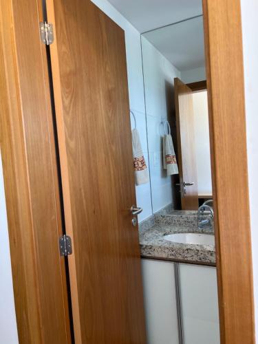 a bathroom door with a sink and a mirror at Apto novo Imperia Lounge pé-na-areia Itacimirim in Itacimirim