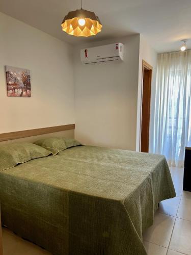 a bedroom with a bed with a green blanket at Apto novo Imperia Lounge pé-na-areia Itacimirim in Itacimirim