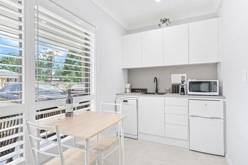 a kitchen with white cabinets and a wooden table at Mala Retreat, Shiraz Suite 5 Star Immaculate and Comfortable in East Maitland