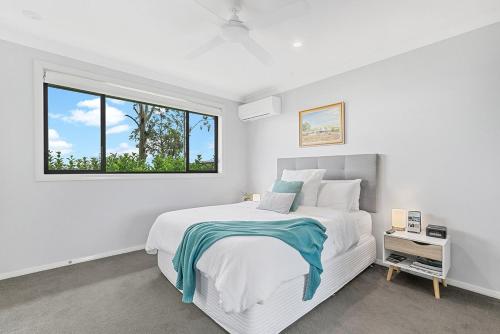 a white bedroom with a large bed and a window at Mala Retreat Chardonnay Studio Immaculate and Comfortable in East Maitland