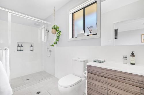a white bathroom with a toilet and a shower at Mala Retreat Chardonnay Studio Immaculate and Comfortable in East Maitland