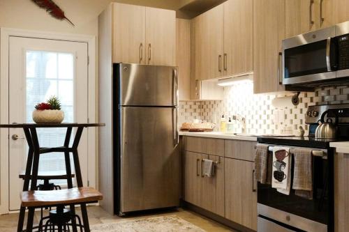 a kitchen with a stainless steel refrigerator and a table at The Nest in 5 Points, Downtown, Walk to Everything in Huntsville