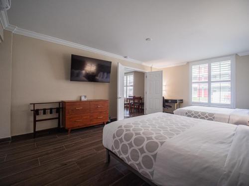 a bedroom with two beds and a dresser and a tv at Equus Inn I75 in Ocala