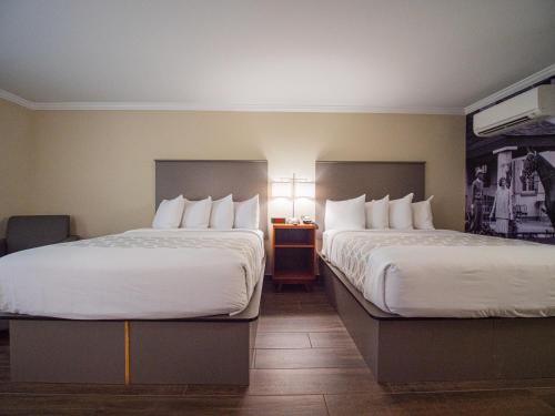 a hotel room with two beds and a table with lamps at Equus Inn I75 in Ocala