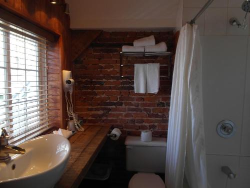 a bathroom with a white sink and a brick wall at Hôtel Manoir de l'Esplanade in Quebec City