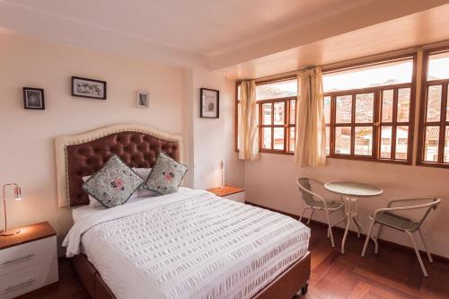 a bedroom with a bed and a table and windows at Cozy Room Cusco in Cusco