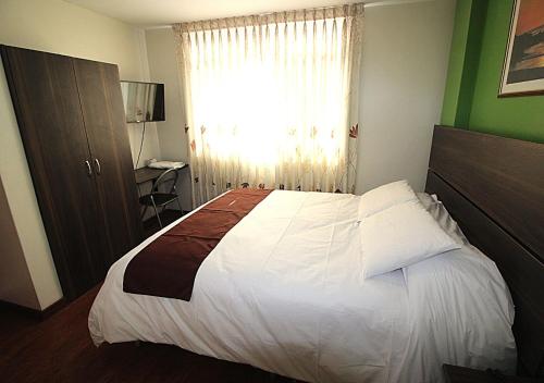 a bedroom with a large white bed with a window at HOSTAL CORAL in Ilo