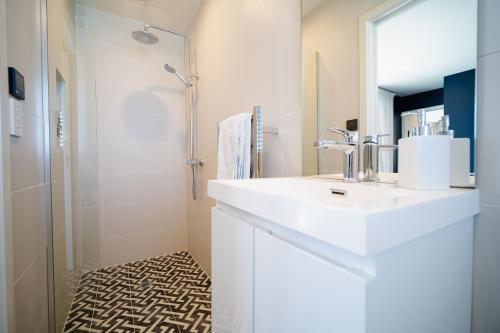 y baño blanco con lavabo y ducha. en Mountain Vista Retreat - Apartment 1, en Twizel