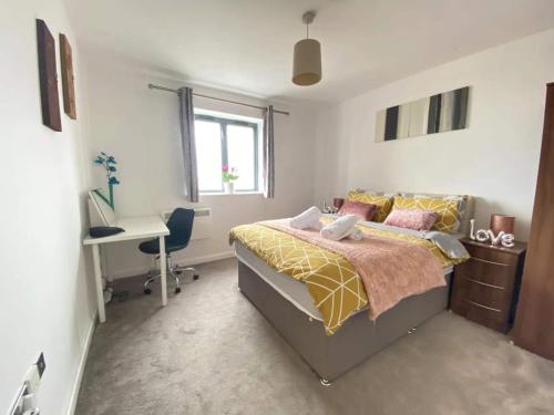 a bedroom with a bed and a desk and a window at Beach Front APT with Stunning Sea View in Swansea