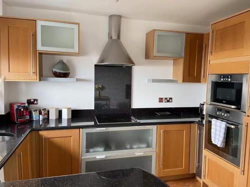 a kitchen with black counter tops and wooden cabinets at Beach Front APT with Stunning Sea View in Swansea