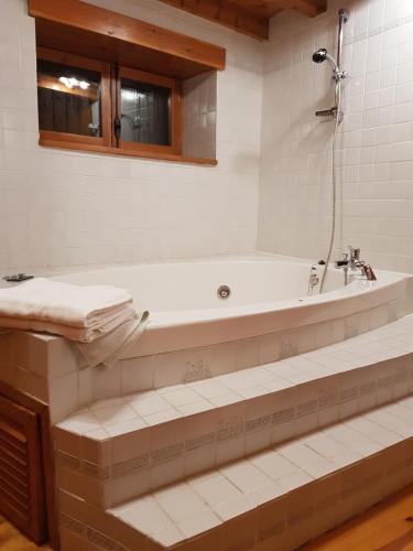 a white bathroom with a tub and a sink at Cal Ferrer del Querforadat in Cava