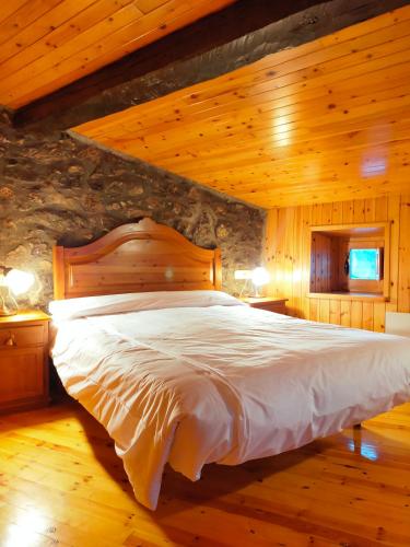 a bedroom with a large bed in a stone wall at Cal Ferrer del Querforadat in Cava