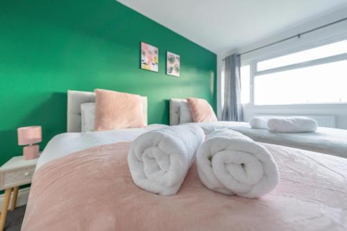 スラウにあるLuxury 3BR Home, Sleeps 5, Contractor Stay -Friendly, Near M25, Free Parkingのベッドの上に白いタオルが2枚置かれた緑の寝室