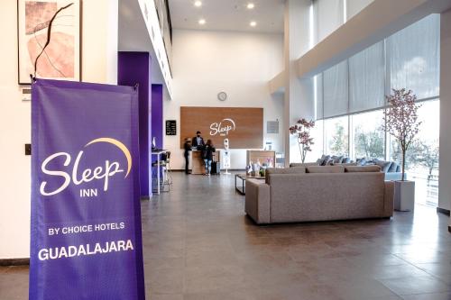 a lobby with couches and a sign in a building at Sleep Inn Guadalajara Galerias in Guadalajara