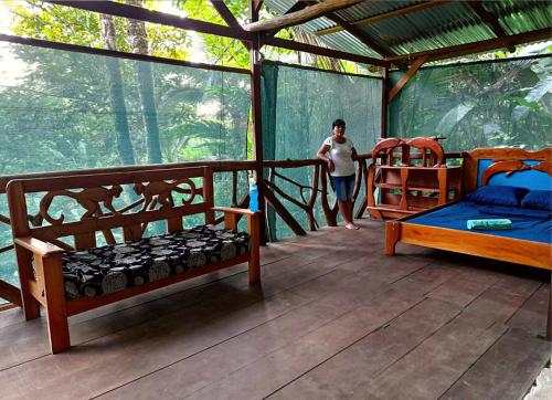 a person standing on the porch of a house with a bed at Corcovado Guide House in Barrigones