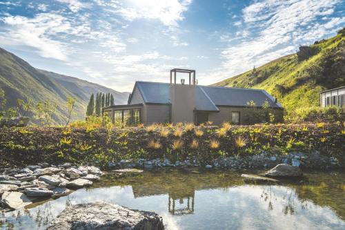 a house on the side of a mountain next to a stream at Gibbston Valley Lodge and Spa in Queenstown