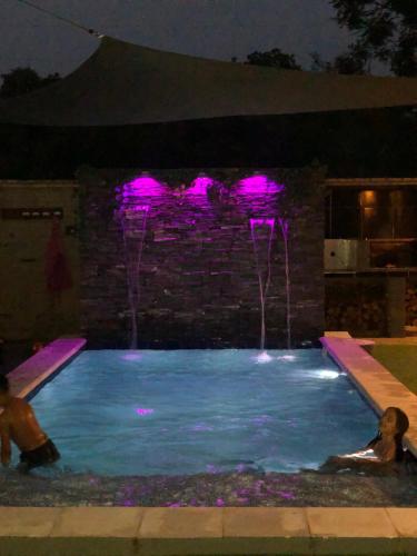 two people in a swimming pool with pink lights at Alquiler San Bernardino Altos Loma grande in Loma Grande