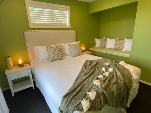 a bedroom with a white bed with a green wall at Mountain Vista Retreat - Apartment 2 in Twizel