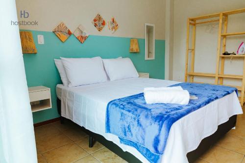 1 dormitorio con 1 cama grande y pared azul en Apto a 200 m da praia do bosque - WIFI 200MB - TV Smart - Cozinha equipada - Garagem - Ar condicionado en Rio das Ostras