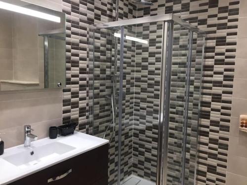 a bathroom with a glass shower with a sink and a shower at AGADIR BAY - LUXURY APARTMENT NEAR BEACH in Agadir
