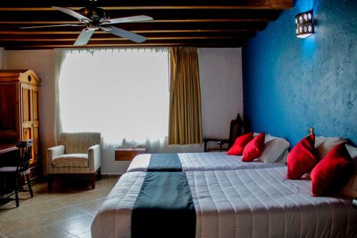 a bedroom with a bed with red pillows and a ceiling fan at Hotel Boutique Don Porfirio in Apaseo el Grande