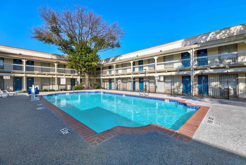 a large swimming pool in front of a building at Studio 6-Denton, TX - UNT in Denton