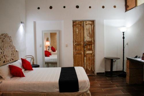 a bedroom with a bed with red pillows and a door at Hotel Boutique Don Porfirio in Apaseo el Grande