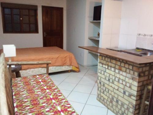 a room with a bed and a table and a bench at Chalé Verde in Barra de Ibiraquera