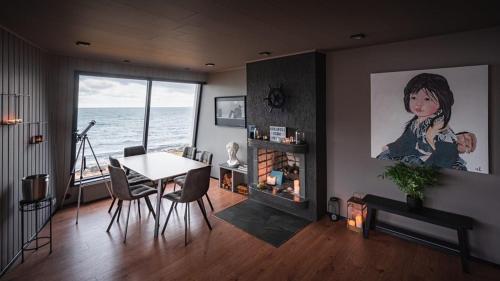 a living room with a dining room table and a painting at Kirkjufell Oceanfront Villa in Grundarfjordur