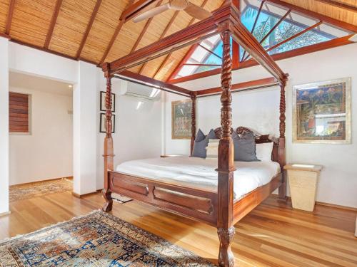 a canopy bed in a room with a wooden floor at Amala Villa in Byron Bay