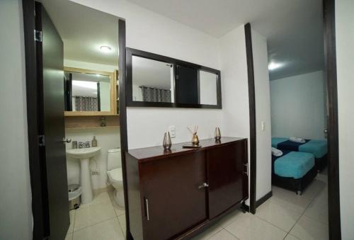 a bathroom with a sink and a toilet and a mirror at Apartamento cerca parque del Café con Piscina in Montenegro