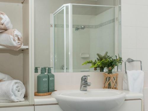une salle de bain blanche avec un lavabo et un miroir dans l'établissement Currumbin Beachfront Haven, à Gold Coast