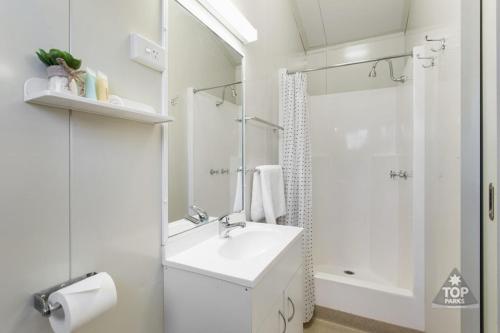 a white bathroom with a sink and a shower at Goondiwindi Holiday Park in Goondiwindi