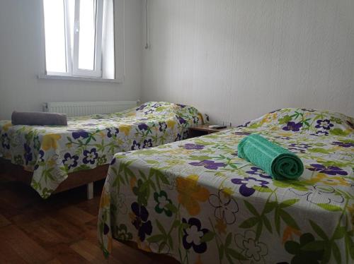 two beds in a room with flowers on them at Bizim Ev hostel in Naftalan