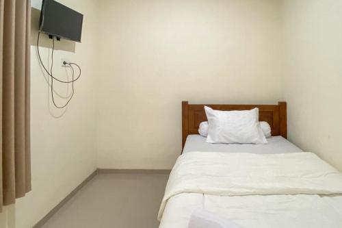 a bedroom with a bed with white sheets and a tv at Nipa Guest House near Universitas Widyagama Mitra RedDoorz in Blimbing