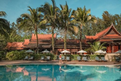 a woman standing in front of a swimming pool at a resort at Khaolak Bhandari Resort & Spa in Khao Lak