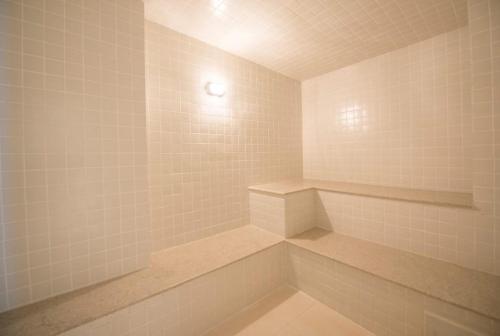 a white tiled shower with a bench in a bathroom at RIO STAY FLAT in Rio de Janeiro